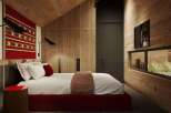 This stunning bedroom boasts a cozy and modern design, featuring a plush bed with a red base, complemented by a textured red and white wall hanging.