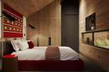This stunning bedroom boasts a cozy and modern design, featuring a plush bed with a red base, complemented by a textured red and white wall hanging.