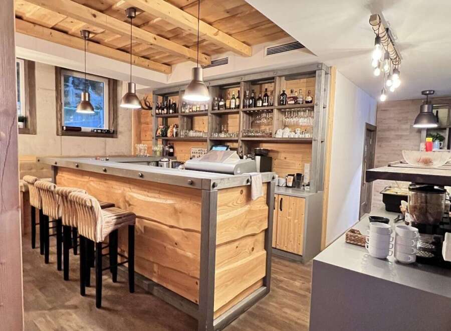 This rustic bar boasts a warm and inviting atmosphere with its wooden accents and stylish pendant lighting.