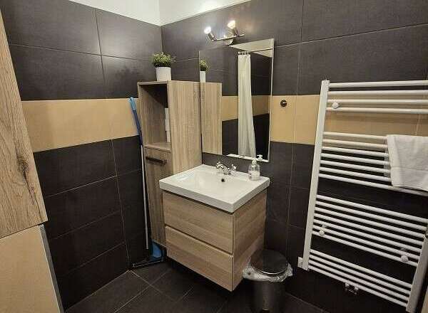 This modern bathroom features sleek dark tile flooring and a stylish vanity with ample storage.