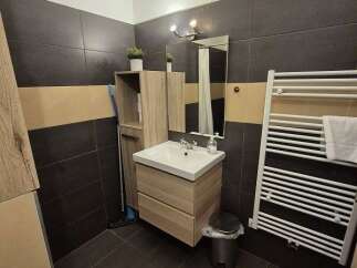 This modern bathroom features sleek dark tile flooring and a stylish vanity with ample storage.