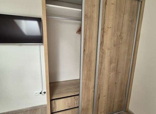 This property boasts a modern design with a stylish wooden wardrobe, offering ample storage space.