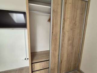This property boasts a modern design with a stylish wooden wardrobe, offering ample storage space.