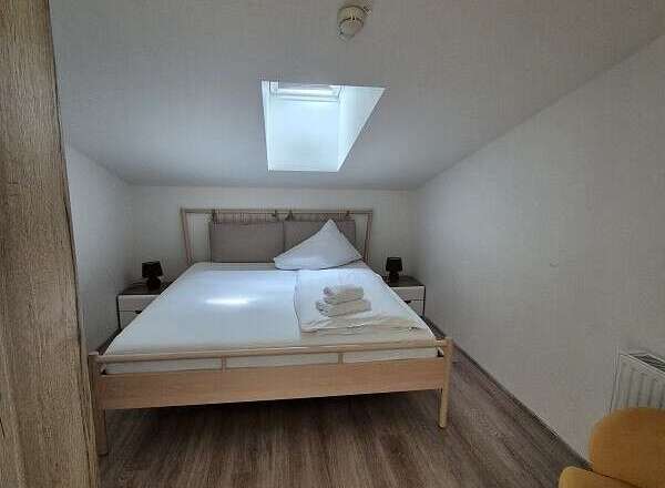 This cozy bedroom features a comfortable bed with fresh linens and a bright skylight.