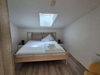 This cozy bedroom features a comfortable bed with fresh linens and a bright skylight.