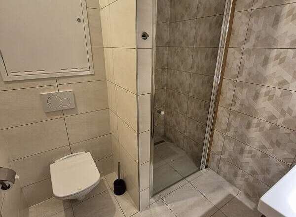 This modern bathroom features a sleek, tiled design with a walk-in shower.
