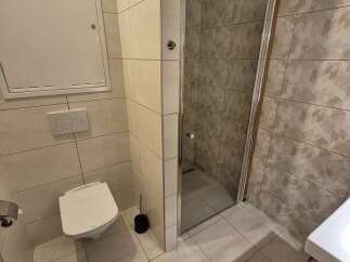 This modern bathroom features a sleek, tiled design with a walk-in shower.