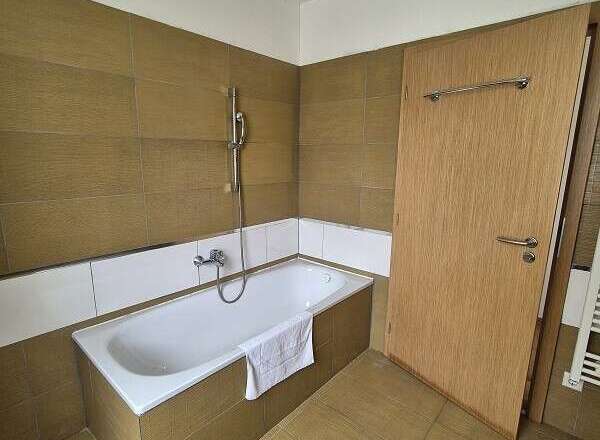 This bathroom features a modern design with a sleek bathtub and a convenient showerhead.
