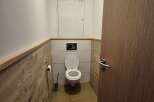 This compact bathroom features a modern design with wood-paneled walls and tiled flooring, creating a warm and inviting atmosphere.