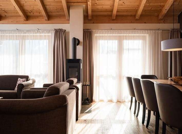 Experience the warmth of this inviting living space, featuring a cozy fireplace and elegant wooden ceiling beams.