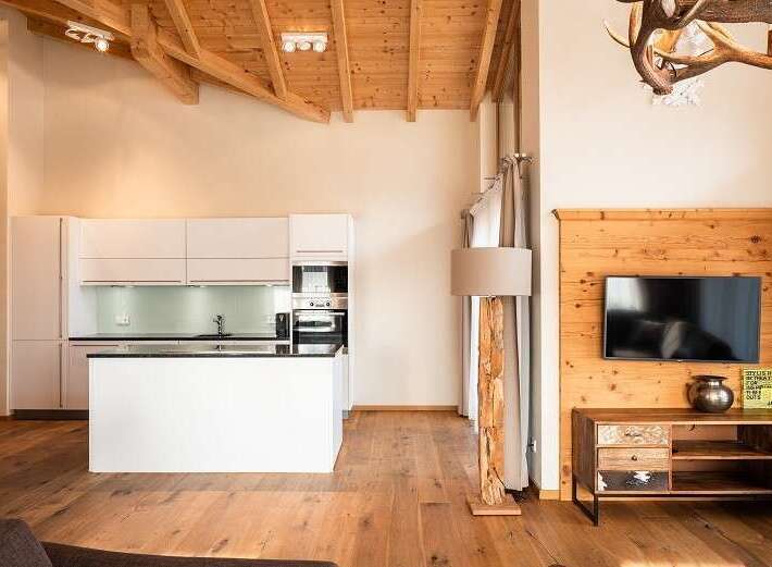 Experience rustic elegance in this stunning property, featuring a modern kitchen with sleek white cabinetry and a stylish island.