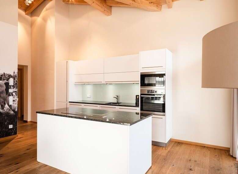 This modern kitchen boasts a sleek design with white cabinetry and a contrasting dark countertop.