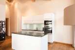 This modern kitchen boasts a sleek design with white cabinetry and a contrasting dark countertop.