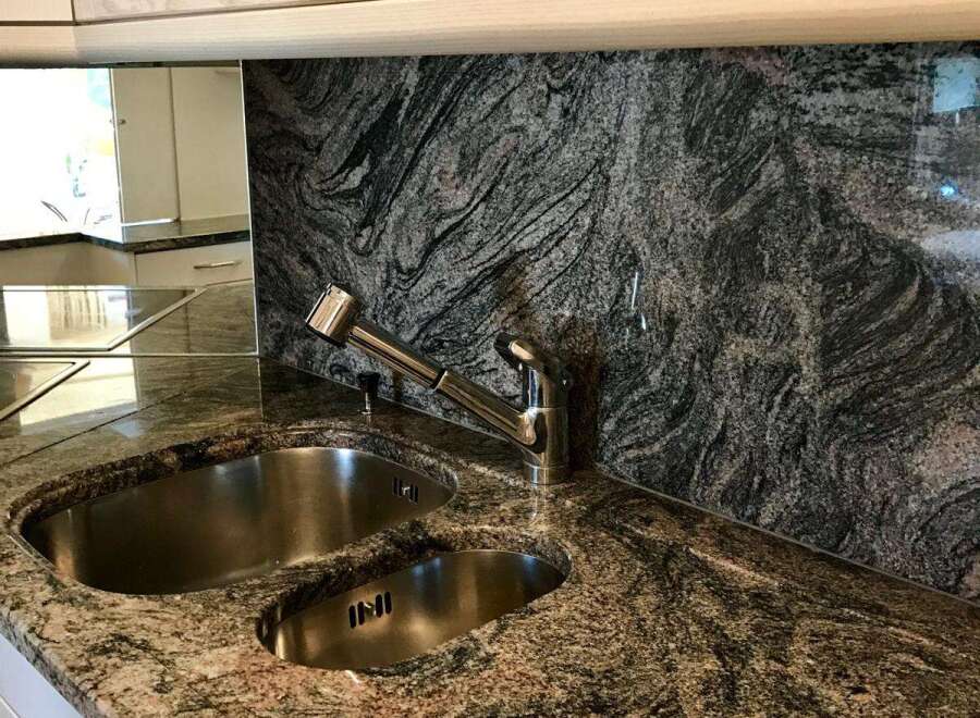 This stunning kitchen boasts a beautiful granite countertop and backsplash, creating a luxurious and durable workspace.
