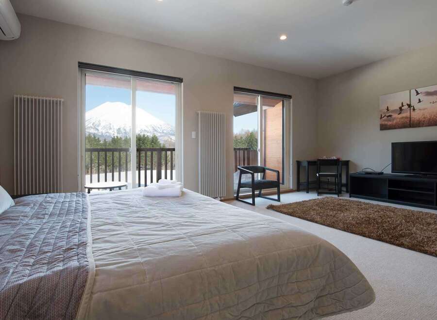 Wake up to breathtaking mountain views from this luxurious bedroom, featuring a plush king-size bed and large windows.