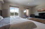 Wake up to breathtaking mountain views from this luxurious bedroom, featuring a plush king-size bed and large windows.