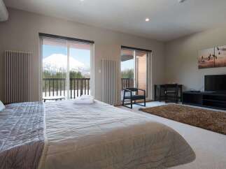 Wake up to breathtaking mountain views from this luxurious bedroom, featuring a plush king-size bed and large windows.