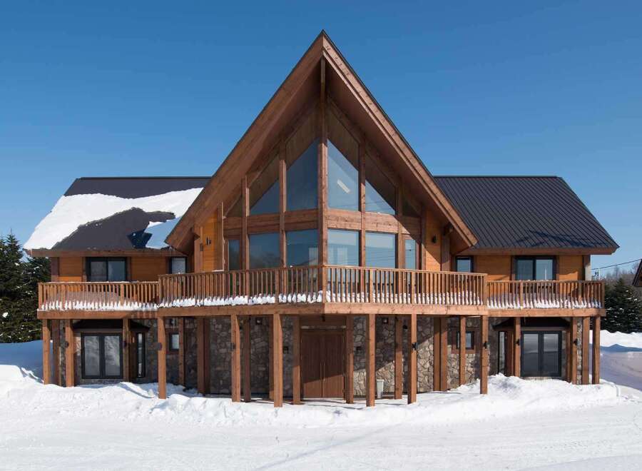 This stunning A-frame chalet boasts a large wrap-around deck, perfect for enjoying mountain views.