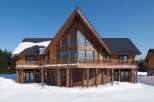 This stunning A-frame chalet boasts a large wrap-around deck, perfect for enjoying mountain views.