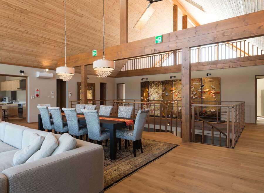 This stunning property boasts a spacious open-plan living area with high ceilings and exposed wooden beams, creating a warm and inviting atmosphere.