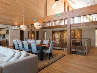 This stunning property boasts a spacious open-plan living area with high ceilings and exposed wooden beams, creating a warm and inviting atmosphere.