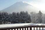 Snowy mountain view from a deck with a wooden railing.