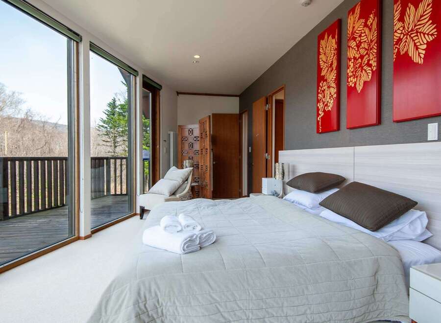 Wake up to breathtaking views from this luxurious bedroom, featuring floor-to-ceiling windows showcasing a stunning mountain landscape.