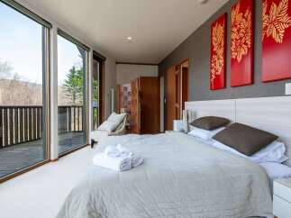 Wake up to breathtaking views from this luxurious bedroom, featuring floor-to-ceiling windows showcasing a stunning mountain landscape.