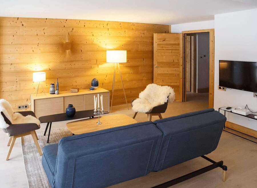 This stunning apartment boasts a cozy living room with a comfortable sofa, sheepskin chairs, and a beautiful wooden wall.