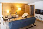 This stunning apartment boasts a cozy living room with a comfortable sofa, sheepskin chairs, and a beautiful wooden wall.