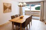 This stunning apartment boasts a spacious dining area with a large wooden table, perfect for family meals.