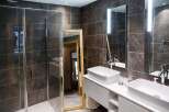 Luxurious bathroom with modern dark gray tiles, double sinks, and a spacious walk-in shower.