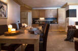 This stunning chalet boasts a spacious, light-filled dining area with a rustic wooden table, perfect for enjoying meals with loved ones.