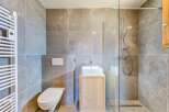 This modern bathroom features a sleek design with gray tile walls and a glass shower enclosure.