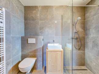 This modern bathroom features a sleek design with gray tile walls and a glass shower enclosure.