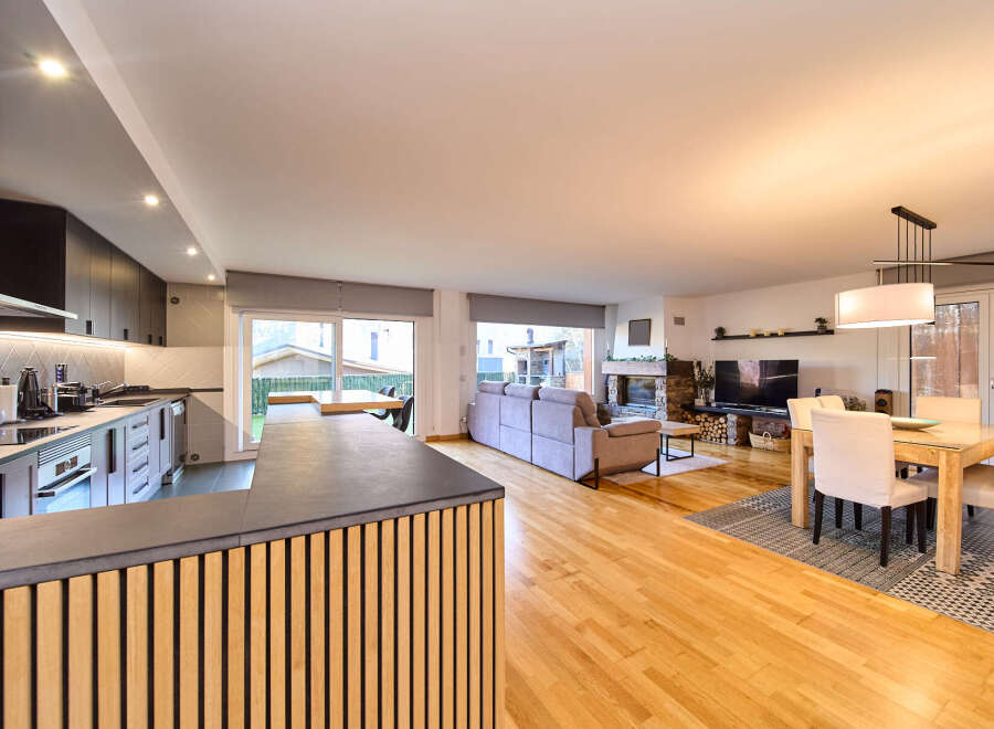 Stunning open-plan living space with sleek modern kitchen, hardwood floors, and a cozy fireplace.