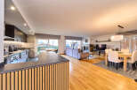 Stunning open-plan living space with sleek modern kitchen, hardwood floors, and a cozy fireplace.