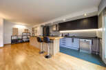 Modern kitchen with sleek dark cabinets and light wood flooring.