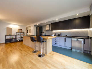 Modern kitchen with sleek dark cabinets and light wood flooring.
