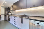 This stunning kitchen boasts sleek dark gray upper cabinets and light gray lower cabinets, complemented by modern black hardware.