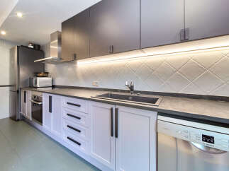 This stunning kitchen boasts sleek dark gray upper cabinets and light gray lower cabinets, complemented by modern black hardware.