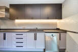 Modern kitchen with dark gray upper cabinets and light purple lower cabinets.