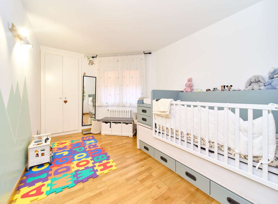Adorable and well-designed baby's room features a modern crib with ample storage, a playful alphabet mat, and a calming color palette.