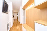 This stunning hallway boasts a modern design with light oak wood paneling and built-in storage, creating a clean and functional space.