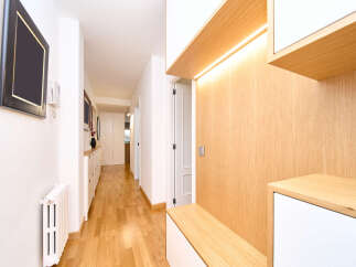 This stunning hallway boasts a modern design with light oak wood paneling and built-in storage, creating a clean and functional space.