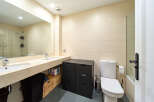 This stunning bathroom boasts modern double sinks, sleek dark cabinetry, and a stylish toilet.