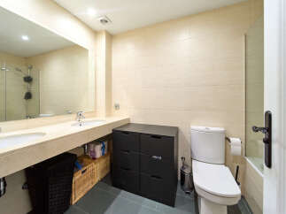 This stunning bathroom boasts modern double sinks, sleek dark cabinetry, and a stylish toilet.