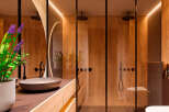 Luxurious bathroom with wooden walls and glass shower enclosure.