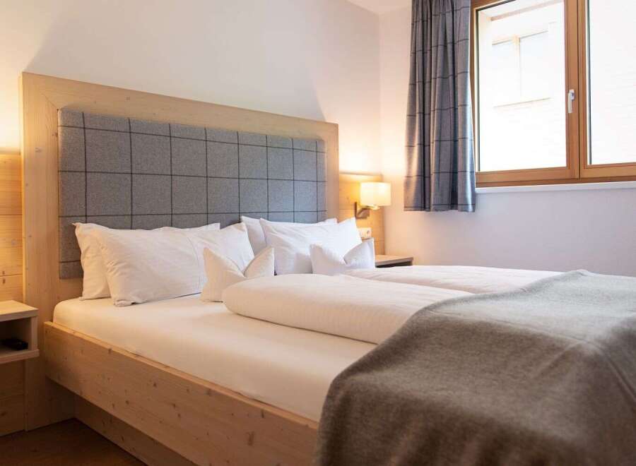 Cozy bedroom with a wooden bed frame and gray plaid headboard.