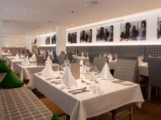 This elegant restaurant boasts a sophisticated ambiance with its plaid-patterned booths, crisp white tablecloths, and tasteful decor.